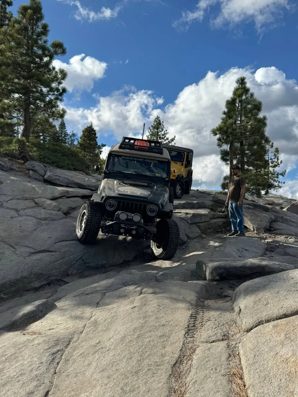 A member standing beside Jeeps navigating a rocky trail